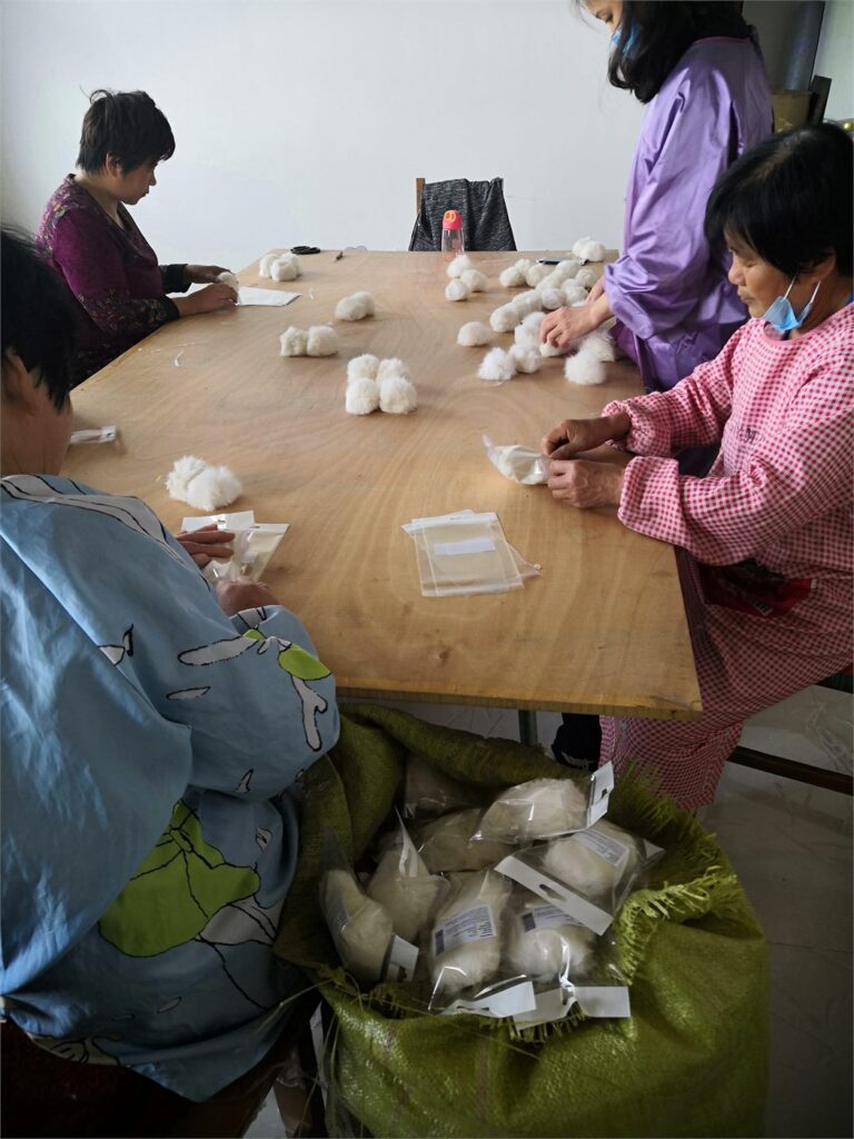 Cornovo team packing small fur accessories individually at a worktable