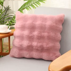 Dusty pink square plush cushion with raised bubble texture on an armchair